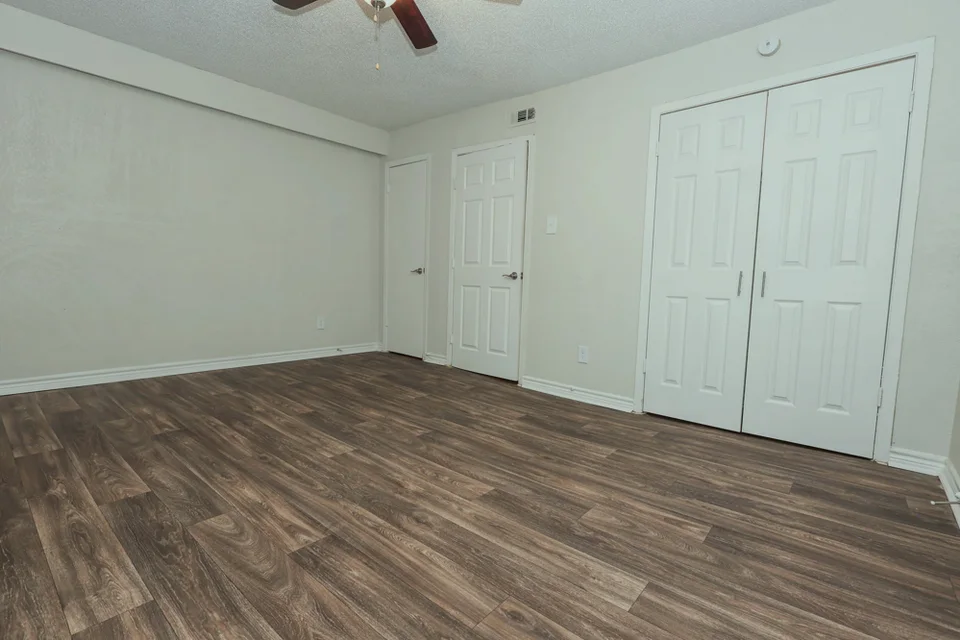 A bedroom with two closets along one wall and a ceiling fan.