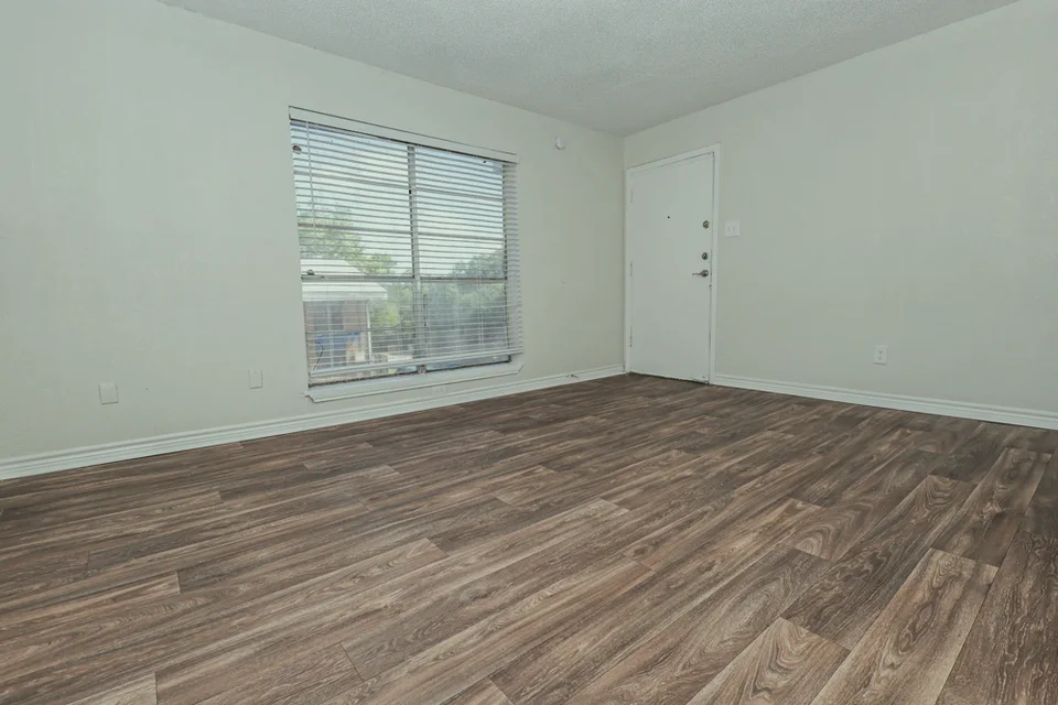 A bedroom with a window and blinds, under a sloped ceiling.