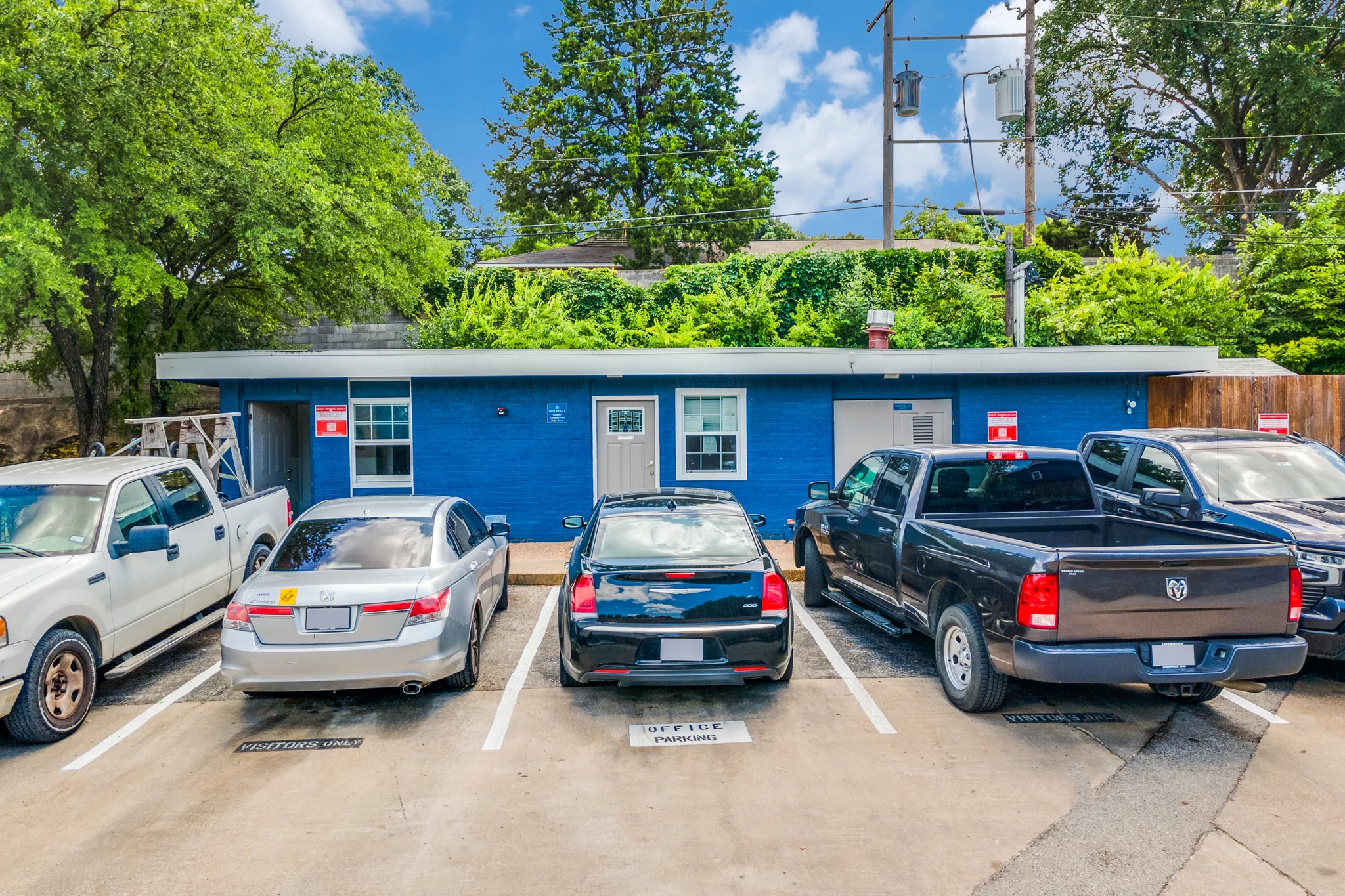 The blue painted leasing office building, beside the visitor parking spaces.