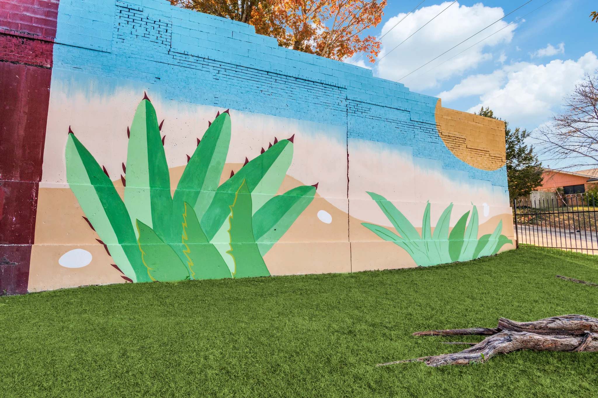 Green agaves hand painted on the brick boundary wall above the lawn.