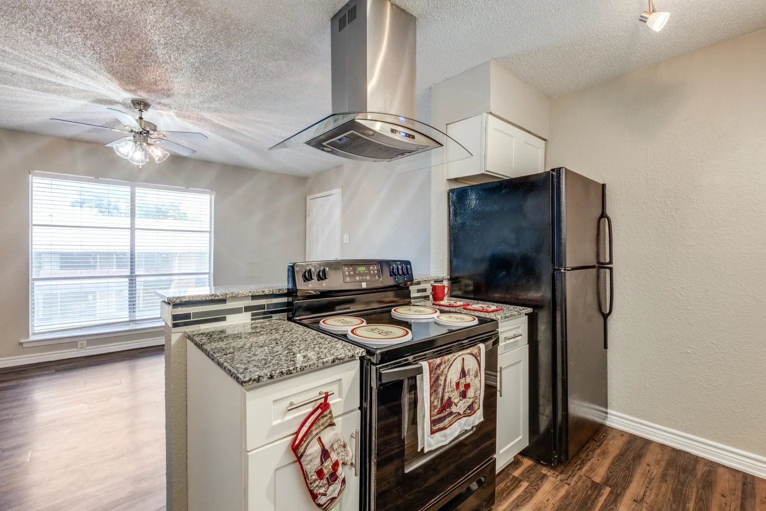 A kitchen with a stainless extractor hood over the range and a window beside it.
