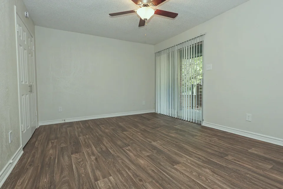 An empty room, a sliding door open to the patio and daylight coming through it.