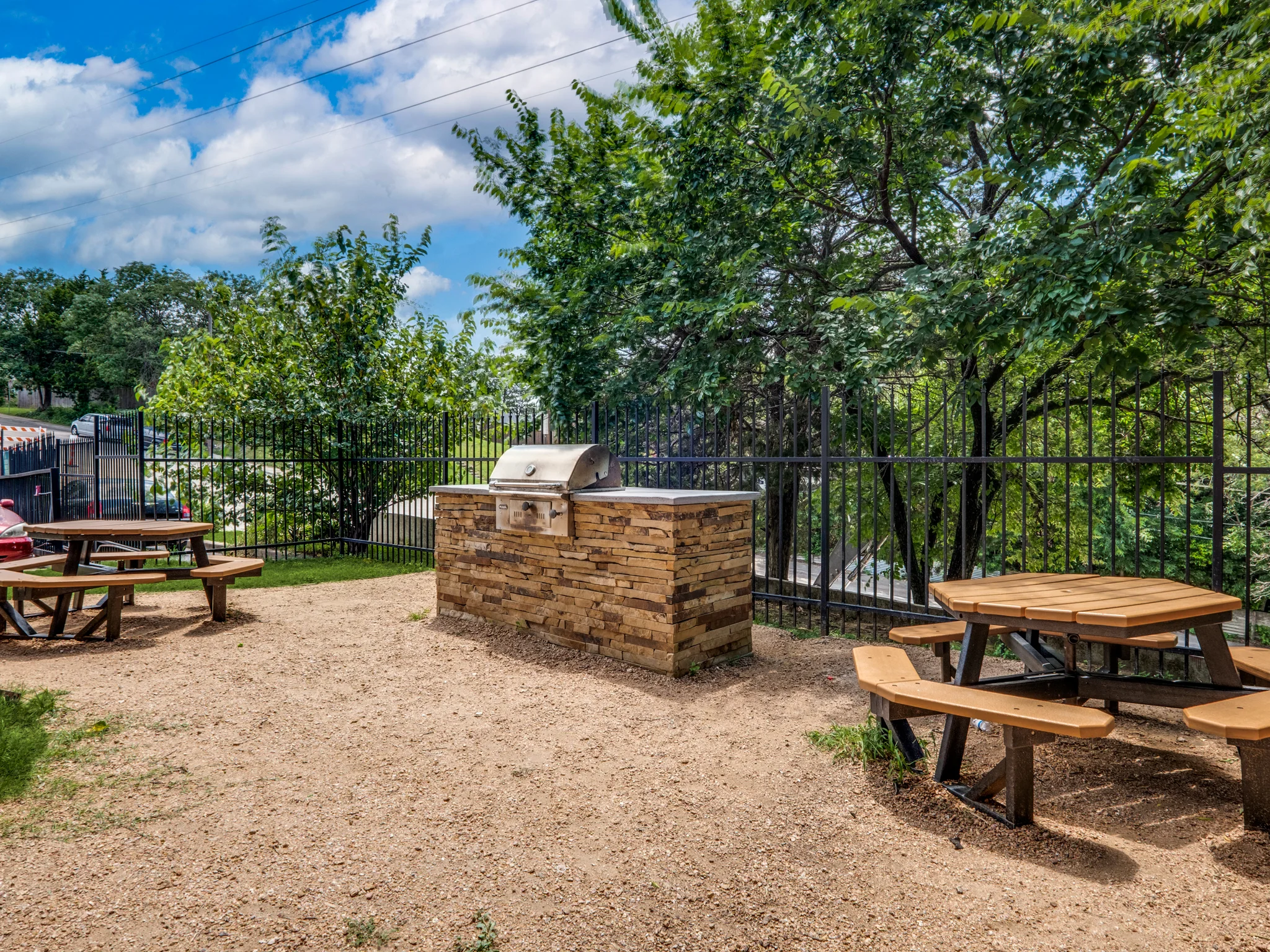 The picnic tables and the grill station under the trees.